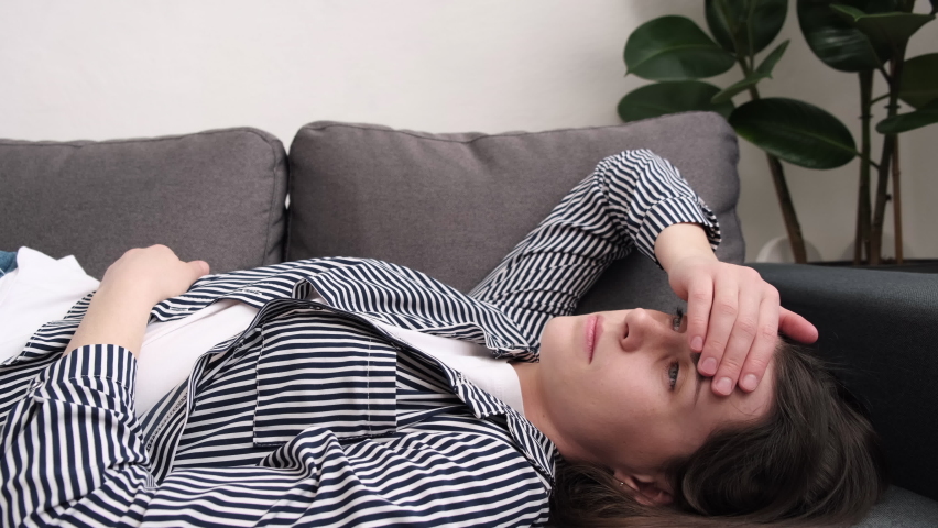 Close up of anxious tired young female lying on sofa feeling doubtful making difficult decision. Nervous unhappy caucasian woman suffering from negative thoughts, relationship problems concept | Shutterstock HD Video #1087021361