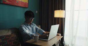 Young attractive asian vietnam man busy work computer or smart tablet on laptop at home in freelance data analyst, data science scientist for business.