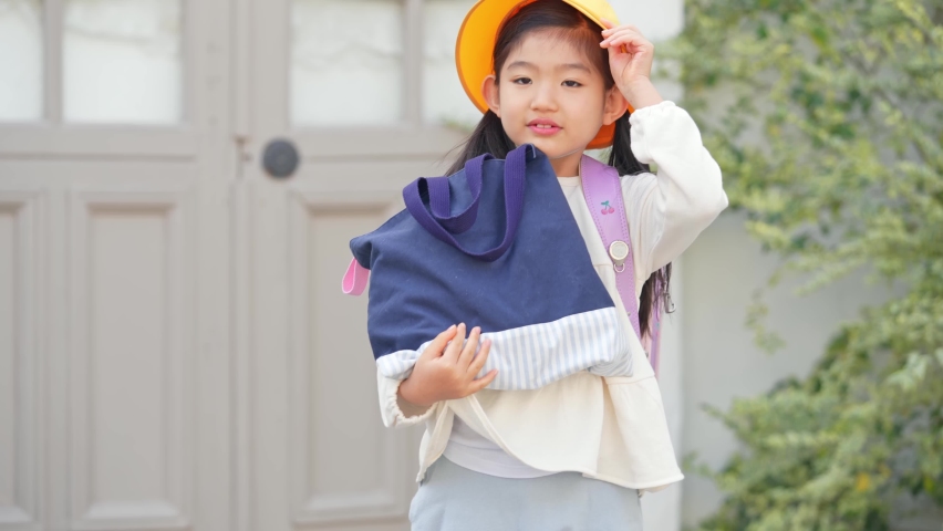 Asian elementary school student carrying a school bag.