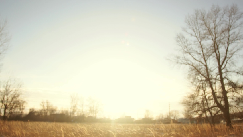 Young adult man reaching to sun with one hand during sunset time in beautiful winter landscape background. 4k of golden sun rays transparent among fingers of male hand isolated on blue sky background