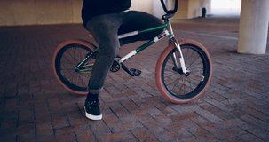His style speaks for him. 4k video of a young bmx biker adjusting his hat while sitting on his bike under a bridge.