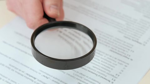Close up video of reading contract with magnifying glass.