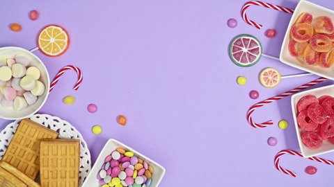 6k Moving sweets, candies and lollipops arrangement on pastel purple background. Stop motion flat lay