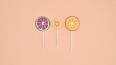 6k Moving fruity lollipops on pastel bright orange background. Stop motion flat lay