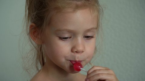 Little girl sucks sweet fruit lollipop. Child eats caramel Chupa Chups. Sweetness