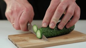Footage of chef cutting fresh cucumber on wooden cutting board