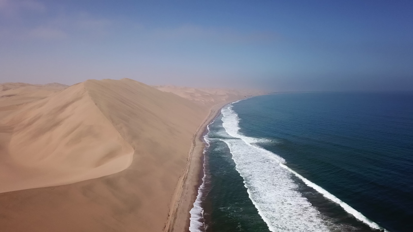 Sandwich Harbour in Namibia at the coast of the Atlantic Ocean. Sandy beach, dunes on the seashore. Summer vacations, wild desert nature in Africa. Namib-Naukluft national park. Royalty-Free Stock Footage #1087033691