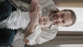 Vertical webcam view caucasian happy family adult bearded dad kiss kid hand and infant newborn small girl little daughter son child waving hands greeting hello to camera video call conference at home 