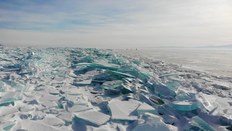 Hummocks, blocks of blue transparent ice near the shore of frozen Lake Baikal. A sunny winter day.
