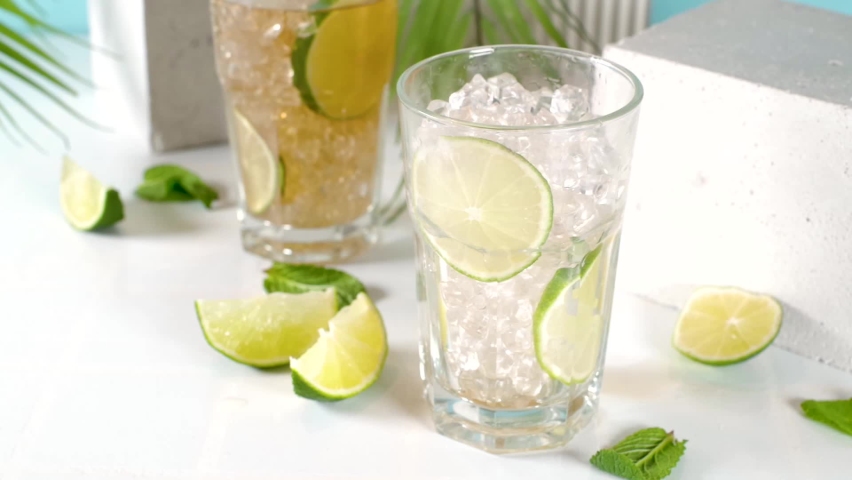 Cuba Libre, long island iced tea cocktail with strong alcohol drink, cola, lime and ice in two glass, cold longdrink mocktail on light blue tiled background Royalty-Free Stock Footage #1087035470