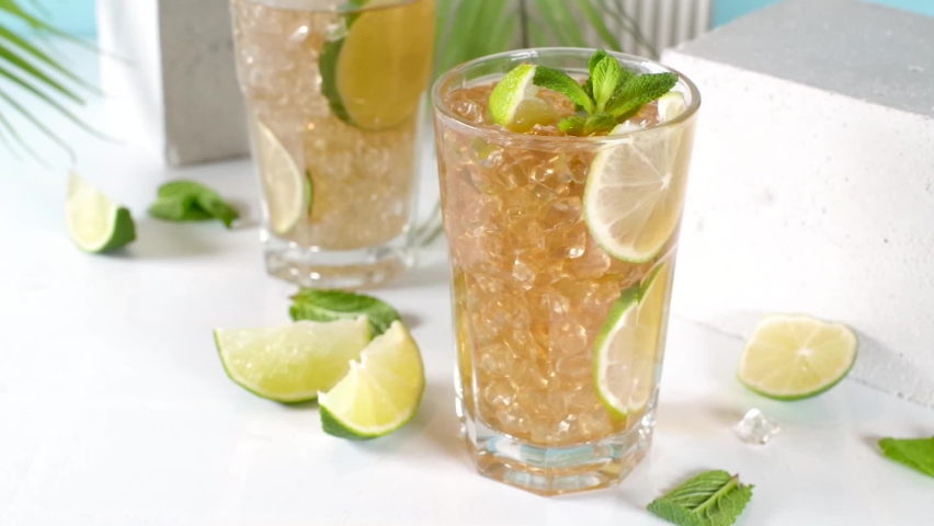 Cuba Libre, long island iced tea cocktail with strong alcohol drink, cola, lime and ice in two glass, cold longdrink mocktail on light blue tiled background Royalty-Free Stock Footage #1087035473