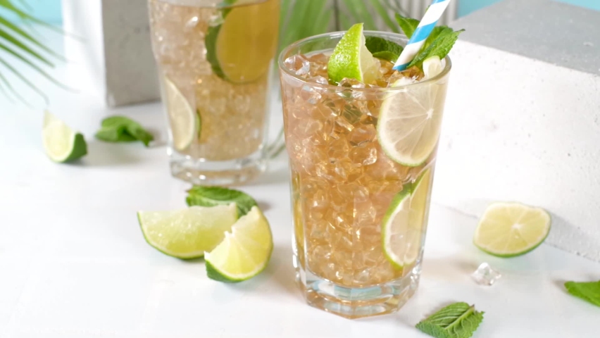 Cuba Libre, long island iced tea cocktail with strong alcohol drink, cola, lime and ice in two glass, cold longdrink mocktail on light blue tiled background