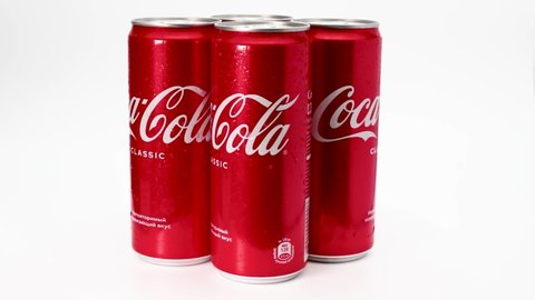 Cans of classic Coca-Cola rotate on a white background. Close-up carbonated soft drink logo. Belarus, Minsk, February 2022.