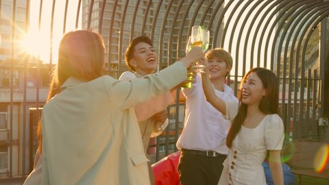 Group of young adults asian gather to celebrate and dance on Friendship Day on rooftop at sunset. Young of transgender and business woman dances and drink alcohol at a party to relaxing.