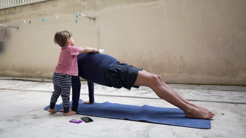 Father doing yoga at home with toddler child next to him