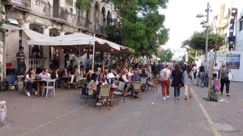 TEL AVIV, ISRAEL – NOVEMBER 29 2021: Walking past busy outdoor terrace of restaurant in Tel Aviv, after many coronavirus restrictions are lifted in Israel