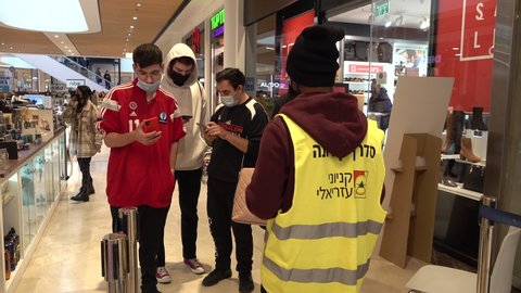 JERUSALEM, ISRAEL – DECEMBER 28 2021: Worker checks QR codes for Green Pass (indicating they are vaccinated against Covid-19) at entrance to food court in shopping mall in Jerusalem, Israel
