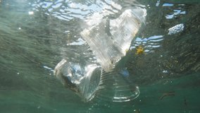 plastic pollution in ocean, underwater video with sun rays. single use or discarded plastics in water. plastic waste problem, environment, earth, ocean, water - Powered by Shutterstock - Get 15% off with code: PIKWIZARD15