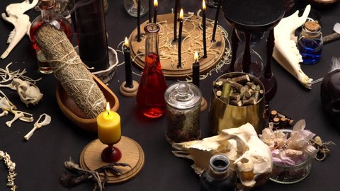 Occult and esoteric witch doctor still life. Selective focus. Halloween background with magic objects. Mortar and pestle, black candle, bones, crystal stones, and potions vials. Mystic witchery weeds.