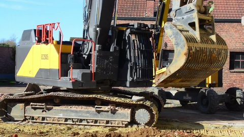 Wilsele, Vlaams-Brabant Belgium - February 15, 2022:  excavator Volvo EC 250 E, the bulldozer grab arm filters the soil. Bulldozer cleaning the earth