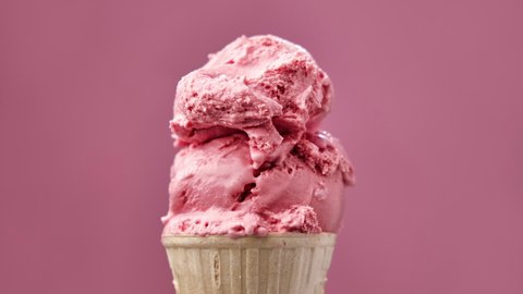 Strawberry ice cream melting on pink background. Timelapse of pink ice cream melting. Close-up of sweet dessert. 4K, UHD