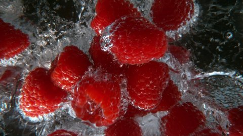 Raspberries falling into water, super slow motion, filmed on high speed cinematic camera at 1000 fps.