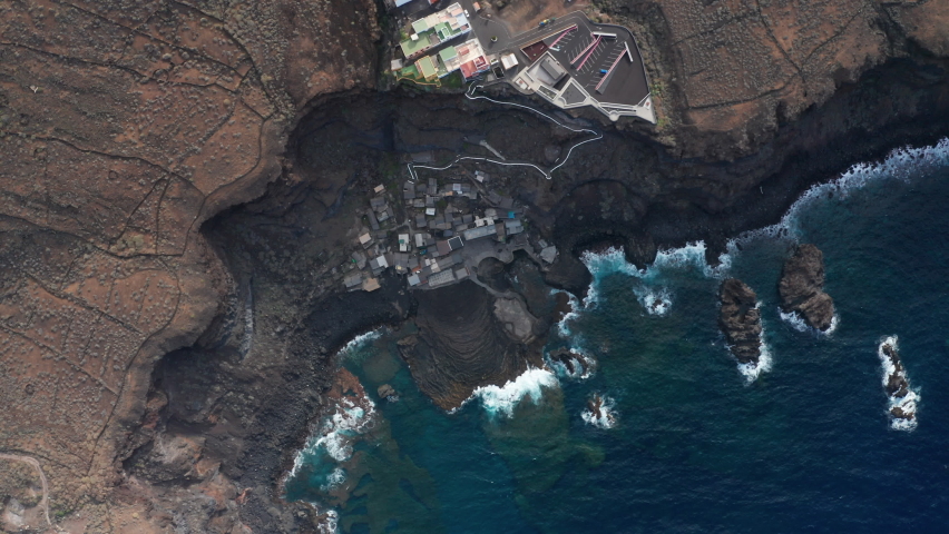 Aerial flat slider on high altitude over the cliff of the volcanic plateau of the coastline of the Atlantic ocean with crystal clear blue emerald water with a clearly visible underwater lava relief