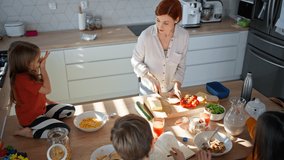 Mother of three little children preparing lunchboxes during breakfast in kitchen at home. - Powered by Shutterstock - Get 15% off with code: PIKWIZARD15