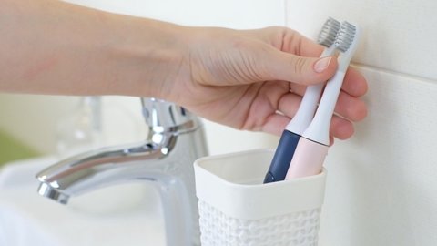 Woman changing old brushes for new modern ultrasonic electric toothbrush. Concept of professional oral care and healthy teeth by using sonic smart toothbrush. Daily life and routine.