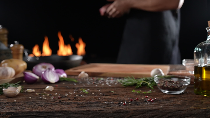 Raw seasoned rib eye steak meat beef dropped on wooden chopping board on a wooden table prepared for cooking with flames in the background. slow motion Royalty-Free Stock Footage #1087069952