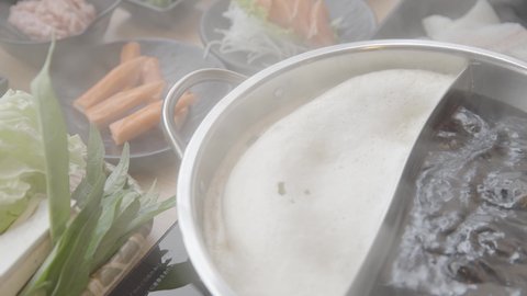 Shabu shabu or sukiyaki japanese style food , Half pot hot boiling in 2 type soup with smoke in a Japanese restaurant