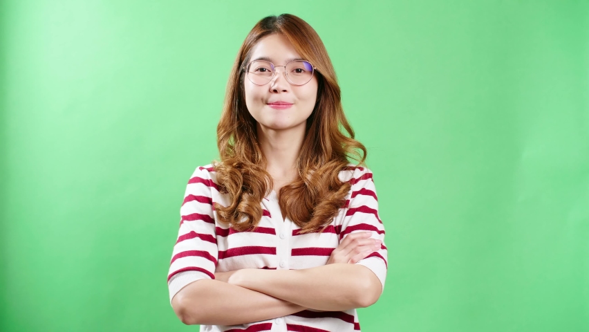 Happy young Asian woman in striped t-shirt wearing eyeglasses looking at camera and smiling joyfully green screen background.