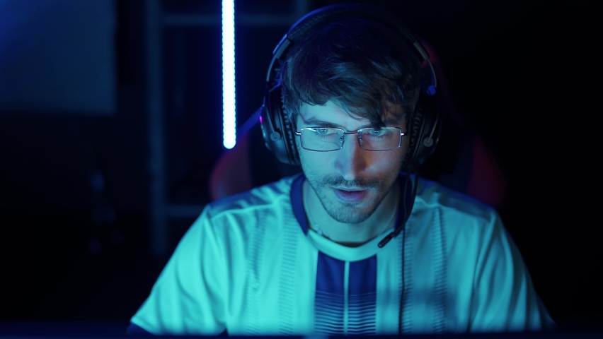 Portrait of a focused man gamer in headphones, plays a video game, cyber sportsman at the international championship, blue neon light.