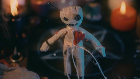 Voodoo doll in ritual scene close up, magic table with candles, witchcraft and spirituality concept