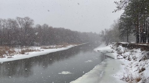 Snowfall over the thawed river Seversky Donets. Winter landscape