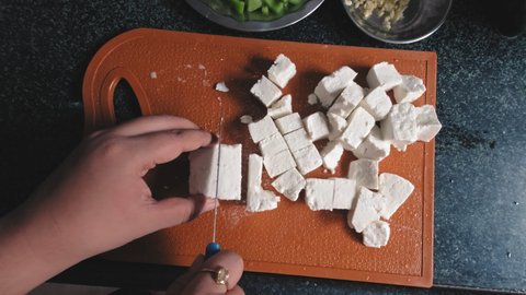 hand Cutting paneer on a board using knife