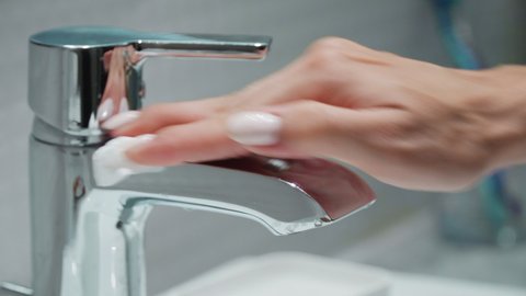 Close-up. A woman's hand wipes the faucet. The girl is cleaning the bathroom. Cleaning service. Hotel cleaning. The maid cleans up the apartment.