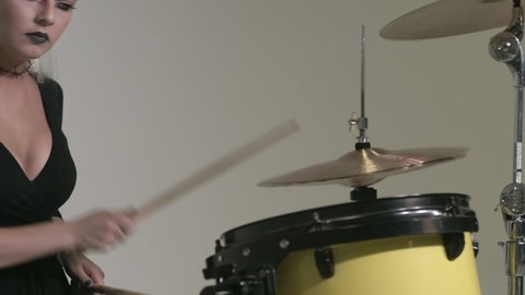 Caucasian girl with a deep neckline and large breasts plays the drums. European girl musician starred in the video. Lady with blue hair. yellow drum set 