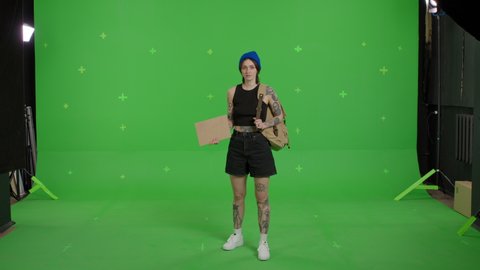 Young beautiful woman hitchhiking holding empty card . Young sexy girl looking for a ride to start a journey over green screen background. Summer time on Chroma Key. 4k uhd video footage