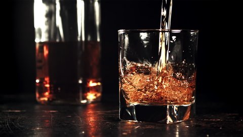 Cognac is poured into the glass with a whirlpool. On a black background. Filmed on a high-speed camera at 1000 fps. High quality FullHD footage