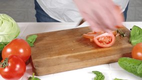 Close-up video of cutting slicing fresh tomatoes. Womans hands cut with knife fresh tomato vegetables