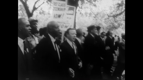 1960s: Martin Luther King Jr. and a mixed race group march in Selma, Alabama. Counter protester hold up a sign. Police pull a man out of a tree and is carried off. Protesters on a sidewalk.