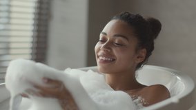 Bath fun. Young carefree african american lady playing with foam in bath, relaxing at bathtub at bathroom interior, slow motion - Powered by Shutterstock - Get 15% off with code: PIKWIZARD15