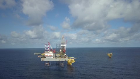 Aerial view from a drone of an offshore jack up rig, oil platform and offshore supply vessels at the offshore location during day time
