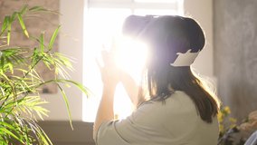 Woman plays with virtual reality glasses on a sunny day. Woman touching something with modern 3d vr glasses indoors.