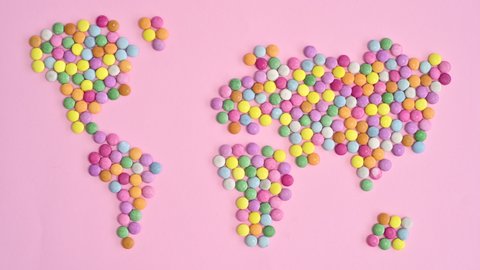 6k Colorful candies make Earth map on bright pastel pink background. Stop motion flat lay concept