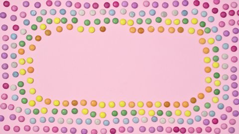 Creative frame pastel pink background with rainbow candies. Stop motion flat lay
