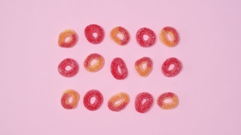 6k Creative layout concept with gummy candies move on bright pink background. Stop motion flat lay