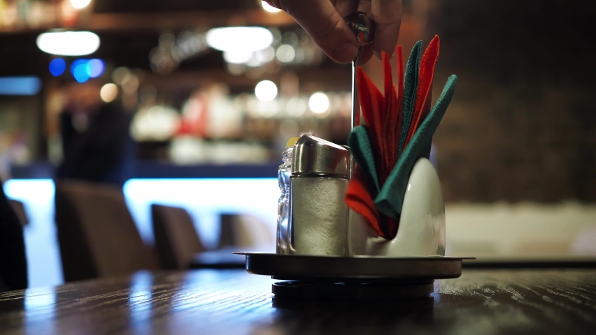 a stand with napkins on the table in a cafe with a blurred bokeh. the people in the background at the bar are blurry bokeh. unrecognizable silhouettes of people in the background