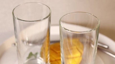 Lassie, a traditional Indian drink, is poured into a glass. In the background are mangoes, metal reusable drinking straws.